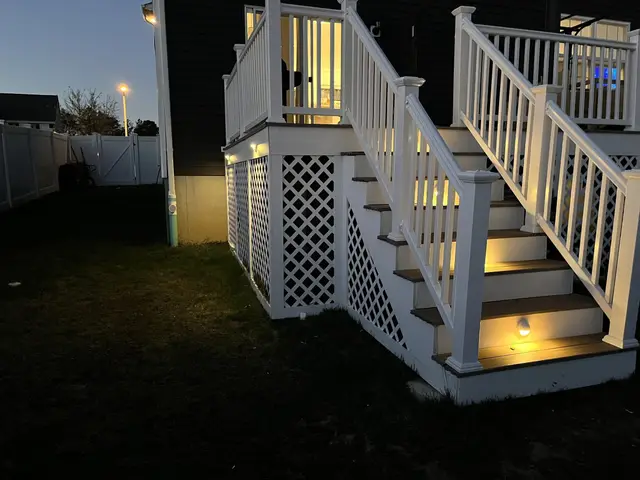 White deck stairs with glowing step riser lights at dusk