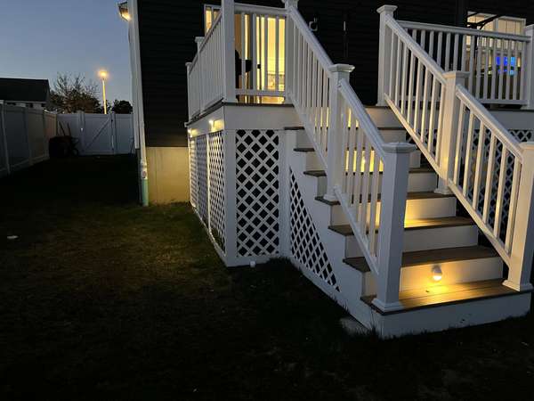 White deck stairs with glowing step riser lights at dusk