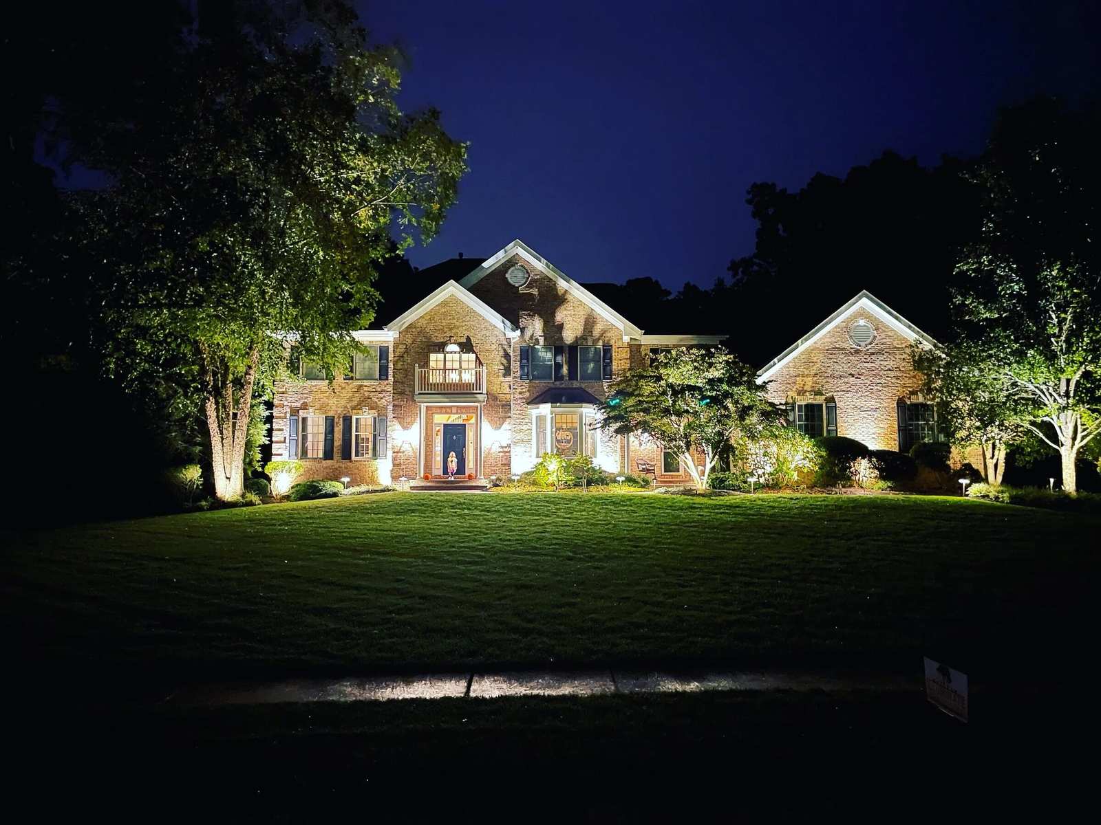 Home exterior lit at night with low voltage facade and landscape lighting