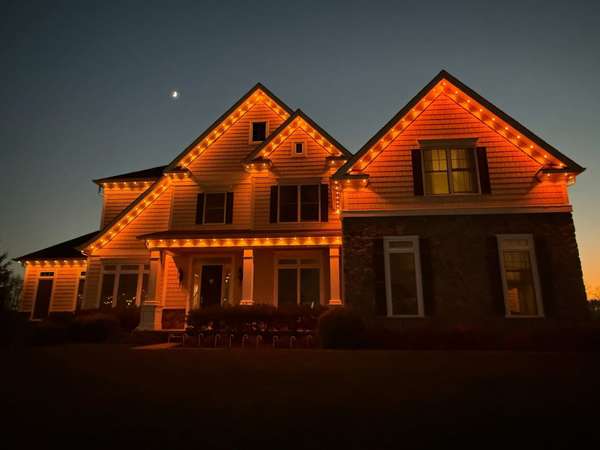 Govee permanent trim lighting in orange along the twin gables and porch roofline of a two-story home at dusk in New Jersey