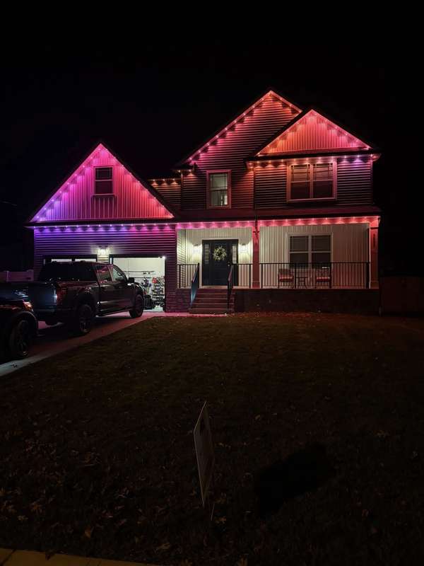 Govee permanent trim lighting fading from pink to purple along the gables and porch roofline of a two-story home at night