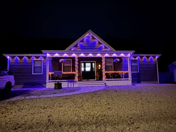 Govee permanent trim lighting in purple along the front gable and full-length porch of a ranch home at night