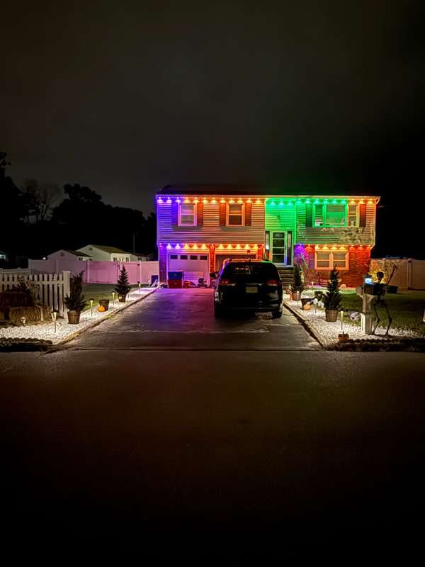 Govee permanent trim lighting in a rainbow of colors along both rooflines of a bi-level home at night, seen from the driveway