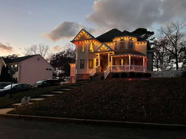 Govee permanent trim lighting in warm white outlining the gables, turret and wraparound porch of a Victorian home on a hill at dusk