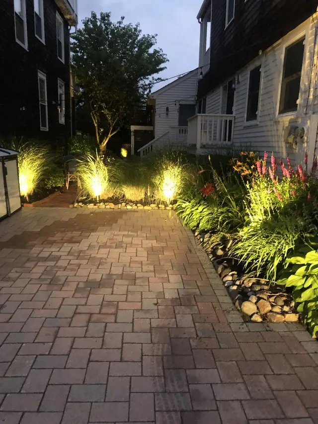 Paver walkway with low voltage accent lights along garden beds