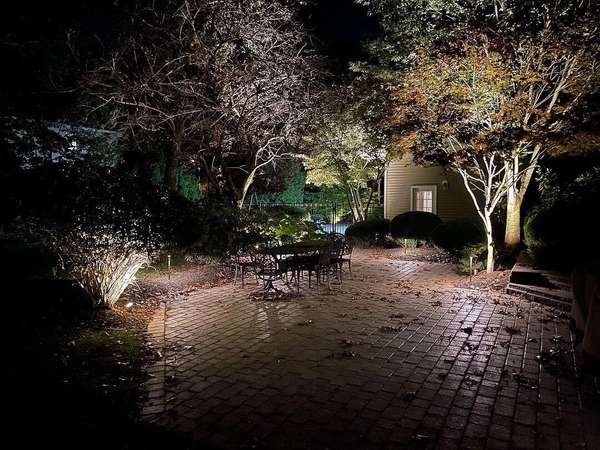 Brick patio with uplit trees and outdoor dining area at night