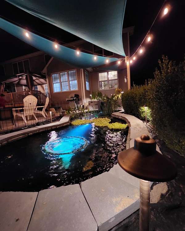 Lit pond and patio under string lights at night